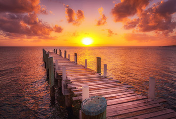 Dock during caribbean sunset, beautiful magenta colors and perspective of this boat dock and fishing dock in Eleuthera island, Bahamas - obrazy, fototapety, plakaty