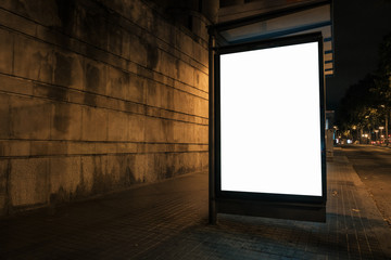 Light box with white blank space for ads at bus stop and wall in background. Night street marketing concept. Horizontal mock-up