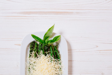 Boiled asparagus with parmesan on a white wooden background