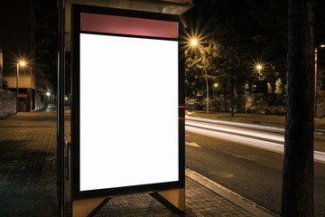 Light box display with white empty space for advertisement at bus station. Horizontal mock-up design concept with car light trails at night.
