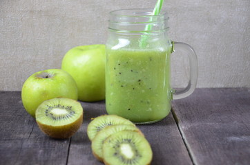 Green healthy smoothie in glass jar: banana, kiwi, green apple on rustic background