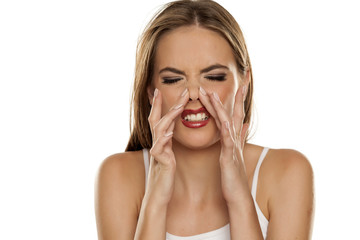 A young woman has itching in the nose on white background