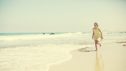 Fototapeta na wymiar 12 years old girl teen girl in yellow dress walking on seaside. Summer vacation
