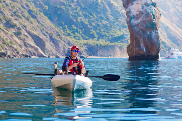 Young Fisherman in a Kayak. Fishing Boat in the sea.