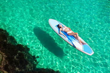 Summer Vacations. Beautiful Young Woman Relaxing on the standup paddleboarding at Turquoise Water. Beauty, Wellness. Recreation.