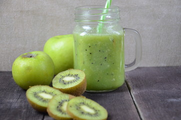 Green healthy smoothie in glass jar: banana, kiwi, green apple on rustic background