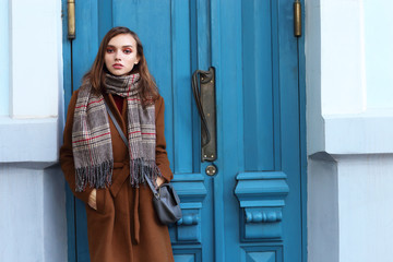 Fashion young woman outdoor. Wearing coat, scarf, and handbag