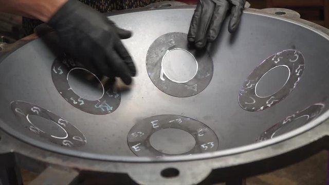 Artisan hands designing Handpan in his workshop, a metal percussion instrument.