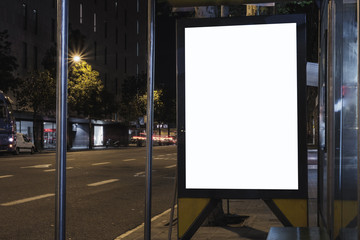 Blank white advertisement lightbox at night. Bus station with empty space for advertising. 