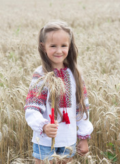 Girl in national costume with embroidery  holding a bouquet of wheat
