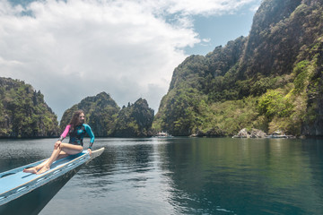 Fototapeta na wymiar Woman relaxing on the boat and looking forward into lagoon. Travelling tour in Asia: El Nido, Palawan, Philippines.