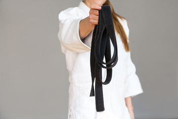 Take it! Female fighter torso poses in white kimono standing and giving you long black belt....