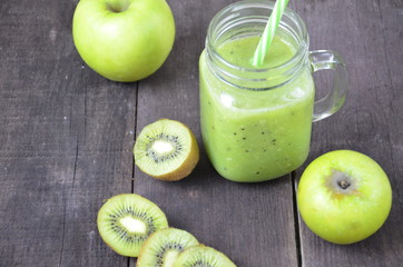 Green healthy smoothie in glass jar: banana, kiwi, green apple on rustic background