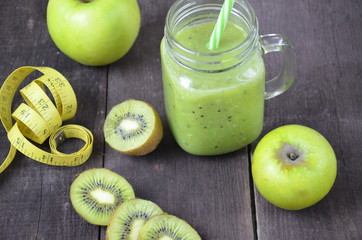 Green healthy smoothie in glass jar: banana, kiwi, green apple on rustic background