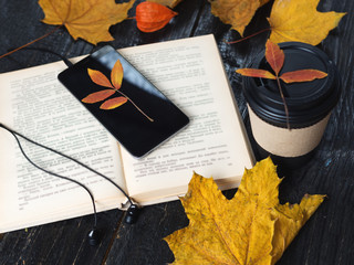 Naklejka na ściany i meble Autumn leaves, coffee, telephone with headphones and audio book concept, modern electronic library