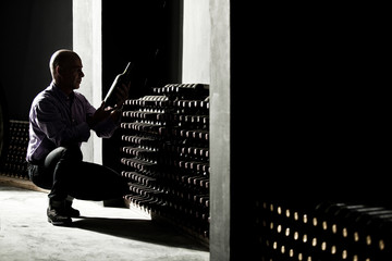 Wine maker checking bottles in a dark cellar