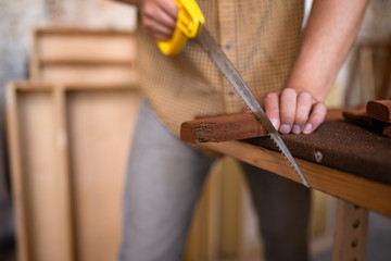 Carpenter saws a board with a hand wood saw. Close-up look on the process of sawing a wooden blank