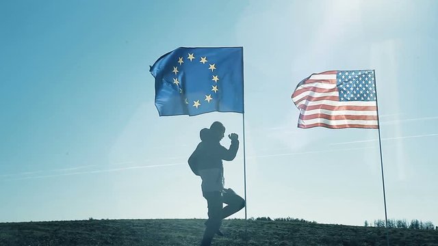 A young man dancing on the background of the EU flag and the flag of America.