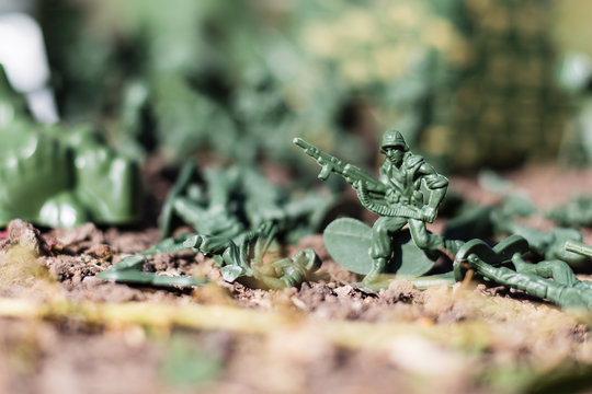 plastic toys. figures of small green armed soldiers fighting each other.