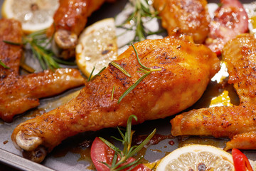 Roasted chicken wings on baking tray over dark wooden background with copy space. Top view, flat lay