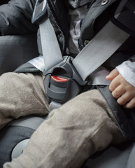 Little baby child fastened with security belt in safety car seat, close-up to the car seat lock
