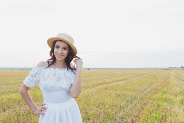 Beautiful young woman in the white dress on the field