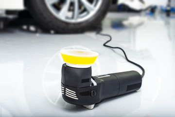 Machine polishing for car care, polishing machine lying on the floor in car detailing service with...