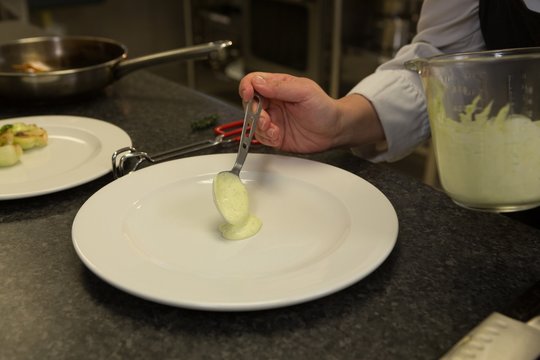 Chef serving sauce on a plate