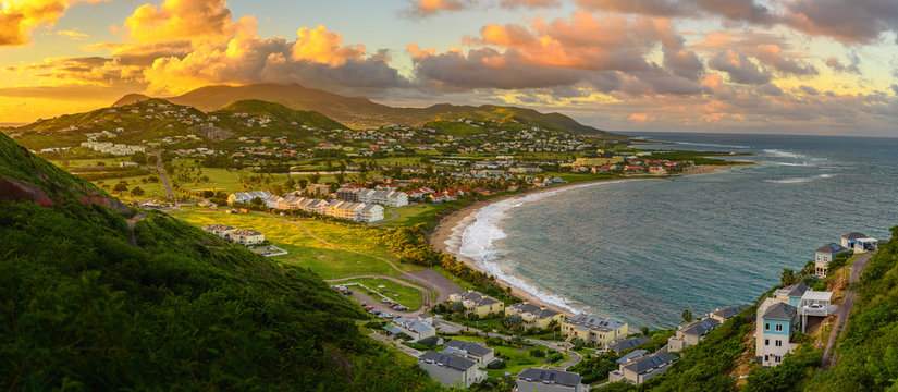 Panorama of Saint Kitts and its capital Basseterre during sunset, beautiful green mountains and a beach in paradise caribbean island with amazing green and orange colors. Saint kitts and nevis
