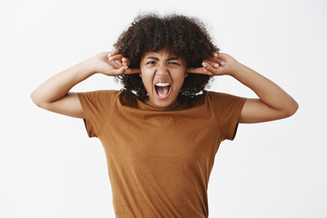 Waist-up shot of fed up pissed off stylish young woman with curly hairstyle in brown t-shirt...
