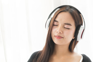 Beautiful Asian pregnant woman using headphone on her belly at home, lifestyle concept.