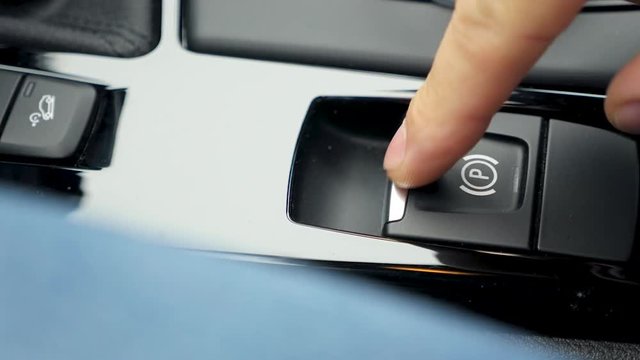 a man pushes the parking brake button