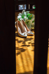 Vertical photo wedding bouquet, bridal shoes and wedding rings on light rays