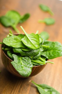 Young Spinach Leaves On Wooden Table And More In Bowl Close-up