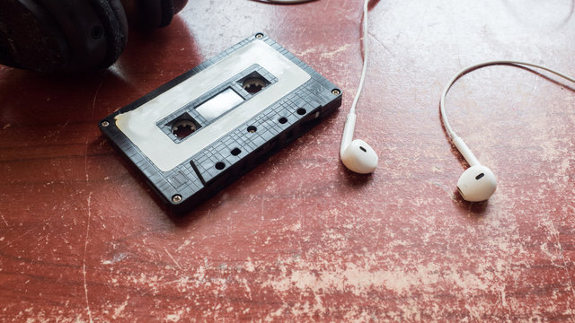 Old cassette tape and player and earphones on the wood background  selective focus  vintage style