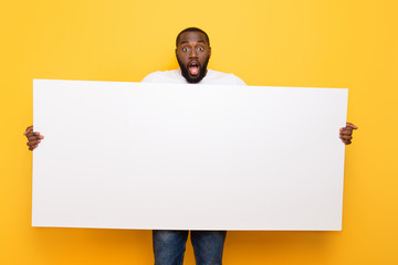 Handsome manly amazed guy showing, holding big wide copy