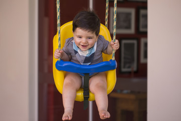 Beautiful brazilian baby boy looking at camera. baby on the swing. Happy baby.