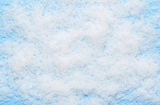 White fluffy artificial snow on blue background. Winter simple background for inscriptions and announcements.