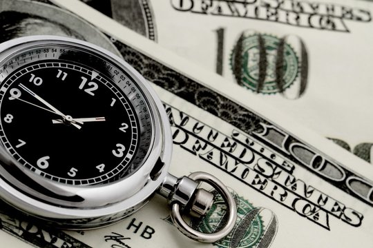 Stop watch/pocket watch on top of a hundred dollar bill