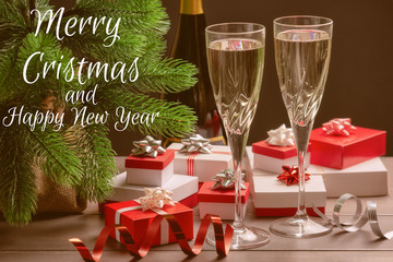 Two glasses of champagne. Many red and white gift boxes, a Christmas tree and decorative ribbons. The inscription Merry Christmas.