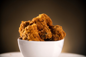 Bucket full of crispy kentucky fried chicken with smoke on brown background. Selective focus.