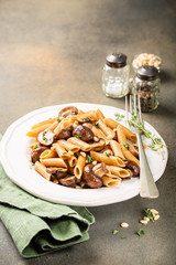 Vegetarian pasta penne with mushroom and pine nuts on kitchen table background. Healthy italian food concept. Copy space.