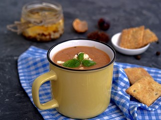 Soup puree from baked aubergines and tomatoes in a yellow mug. Served with feta cheese and crackers.