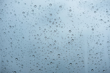 raindrops on glass window of car with cloudy sky in the background