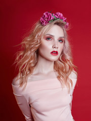 Portrait of sexy fashion beautiful blonde woman with bright makeup posing on red crimson background. Slender blonde girl, perfect figure and long hair. Clean perfect face skin