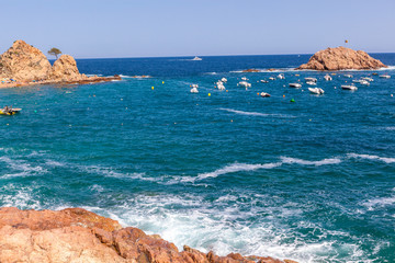 Tossa De Mar beach, waves hitting shore, rock cliffs and rock islands 