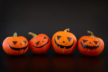 Pumpkins with painted faces on black background. Halloween backdrop.