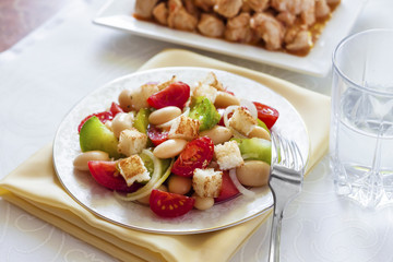Salad with three kinds of tomatoes, boiled white kidney beans and croutons from white bread