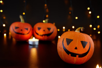 Pumpkins with painted faces on black background. Halloween backdrop.