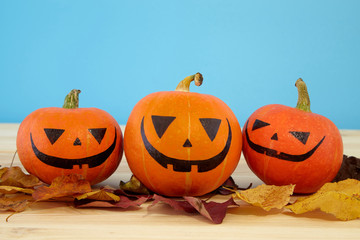 Pumpkins with painted faces on blue background. Halloween backdrop.